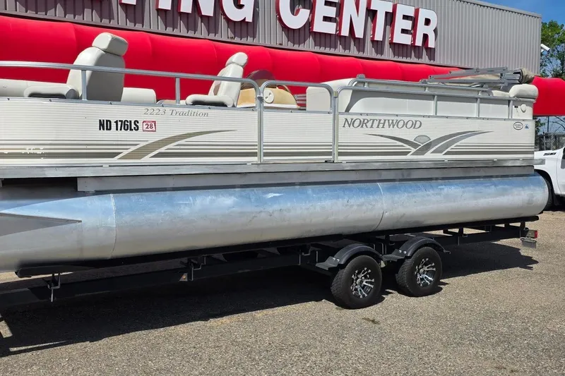 Slide: The Image of 2003 Northwood 2223 Traditions pontoon boat on trailer outside a boating center. - 1