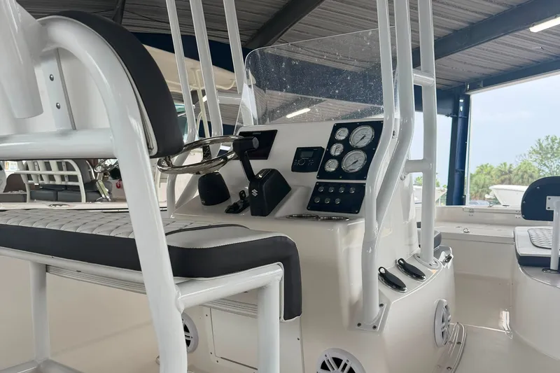 Slide: The Image of 2025 Clearwater 21 Bay boat interior with steering console and seating under a canopy. - 6