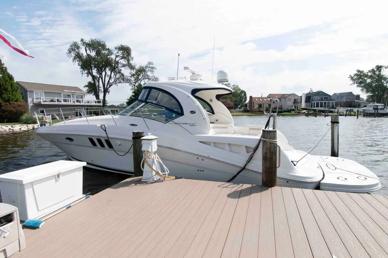 The Image of 2009 Sea Ray Sundancer 400 yacht docked at a marina, surrounded by waterfront homes. - 0