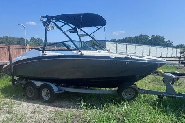 Slide: The Image of 2013 Yamaha Boats 212X on trailer, parked outdoors with a blue canopy. - 4
