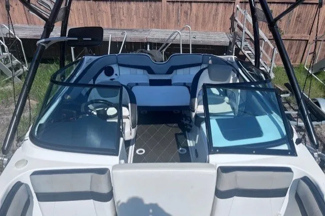 Slide: The Image of 2013 Yamaha Boats 212X interior with seating and steering wheel, docked outdoors. - 5