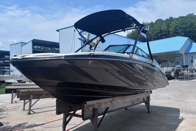 The Image of 2013 Yamaha Boats 212X on display at a marina with blue-roofed buildings. - 1