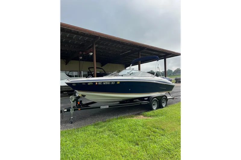 Slide: The Image of 2010 Four Winns H210 boat on trailer under shelter, parked on grass. - 2