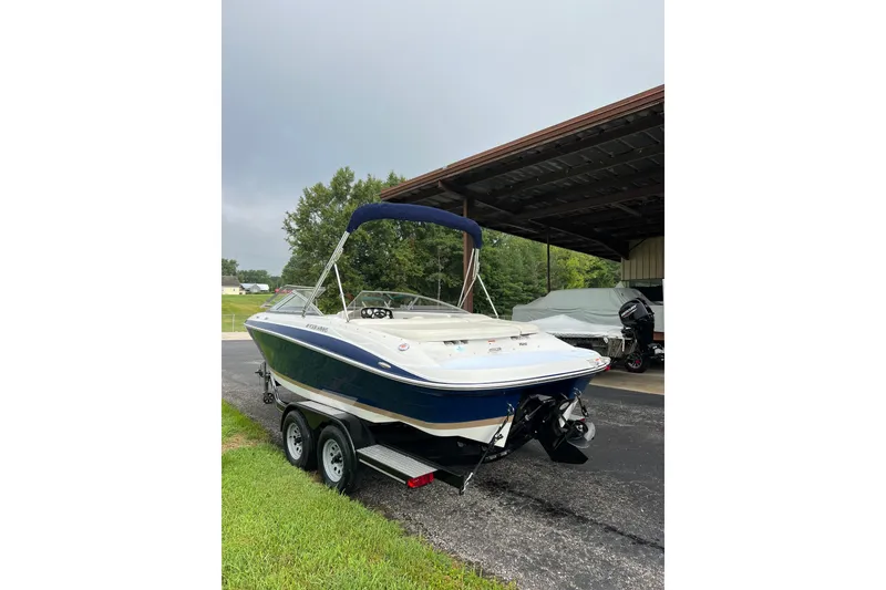 Slide: The Image of 2010 Four Winns H210 boat on trailer, parked outdoors under cloudy sky. - 3