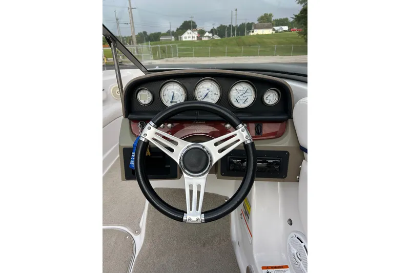 Slide: The Image of Steering wheel and dashboard of 2010 Four Winns H210 boat, featuring gauges and controls. - 6