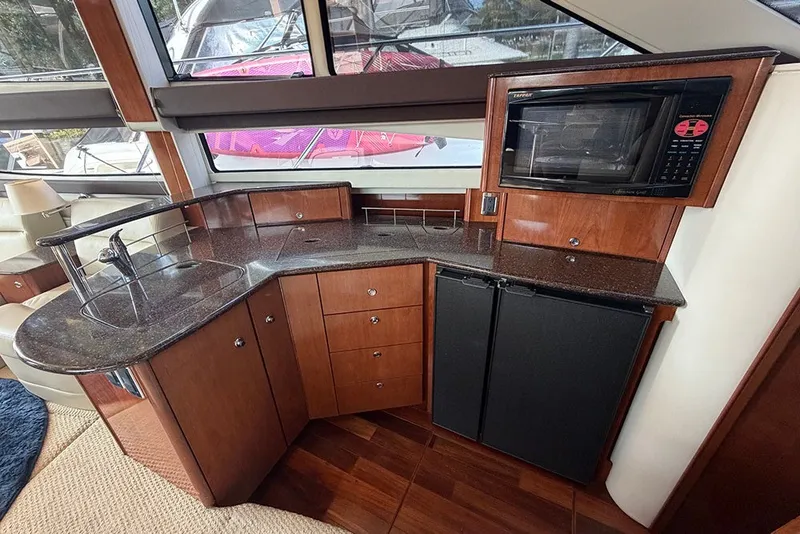 Slide: The Image of Luxurious 2009 Meridian 391 Sedan yacht interior with kitchenette, featuring wood cabinetry and modern appliances. - 13