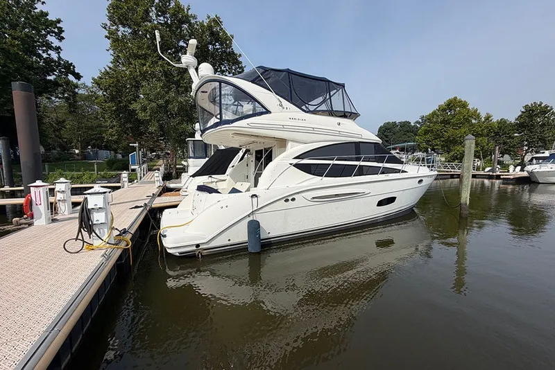 Slide: The Image of 2009 Meridian 391 Sedan yacht docked at a marina, surrounded by calm water and trees. - 4