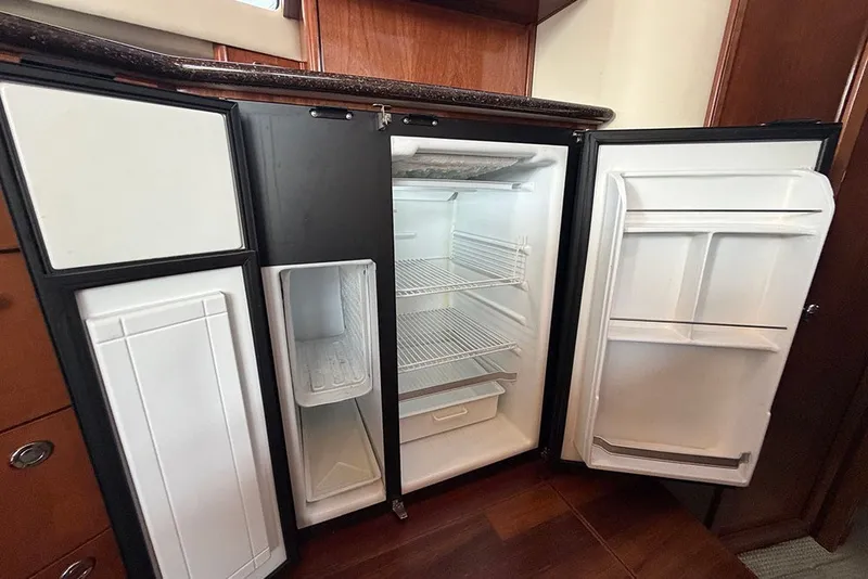 Slide: The Image of Open refrigerator inside 2009 Meridian 391 Sedan yacht, featuring spacious shelves and storage compartments. - 14