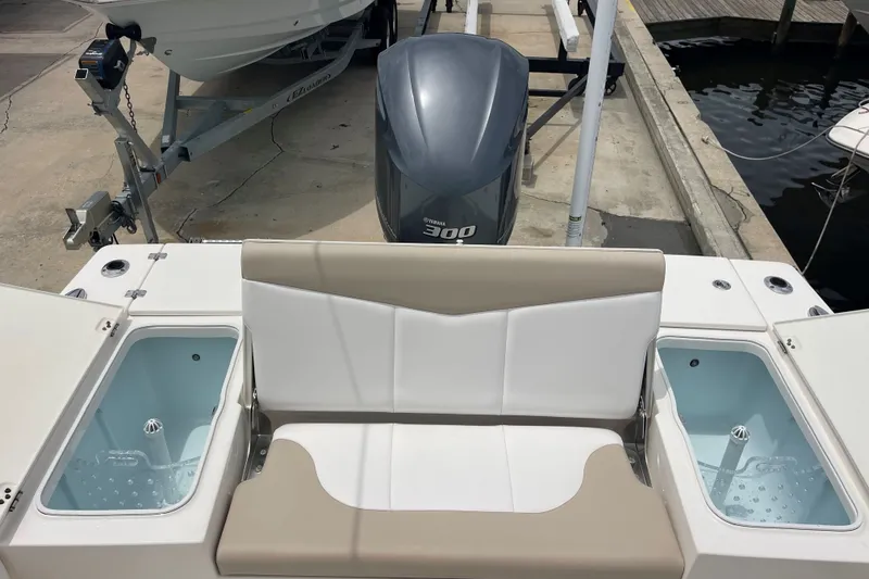 Slide: The Image of 2019 Robalo 246 Cayman boat interior with seating and live wells, docked near water. - 18