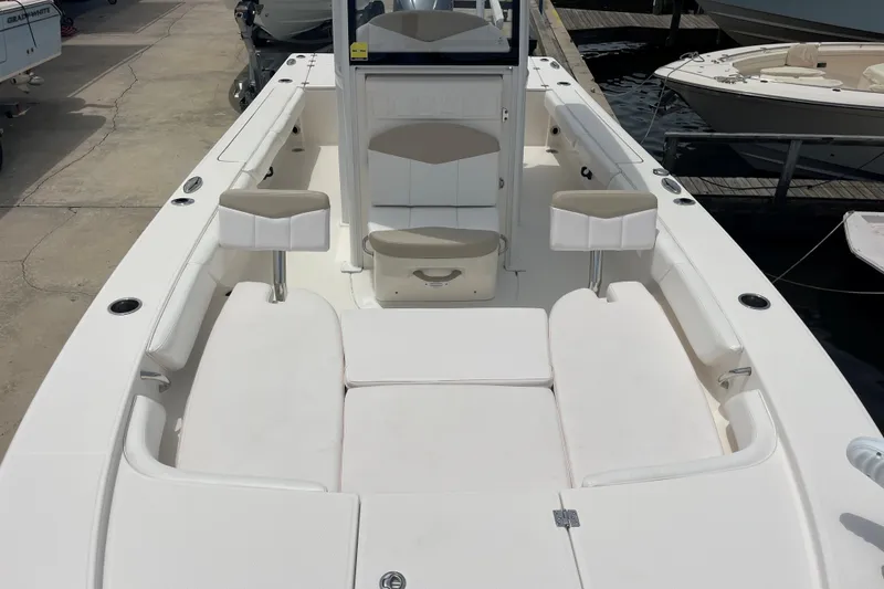 Slide: The Image of 2019 Robalo 246 Cayman boat interior with white seating and console, docked at marina. - 31