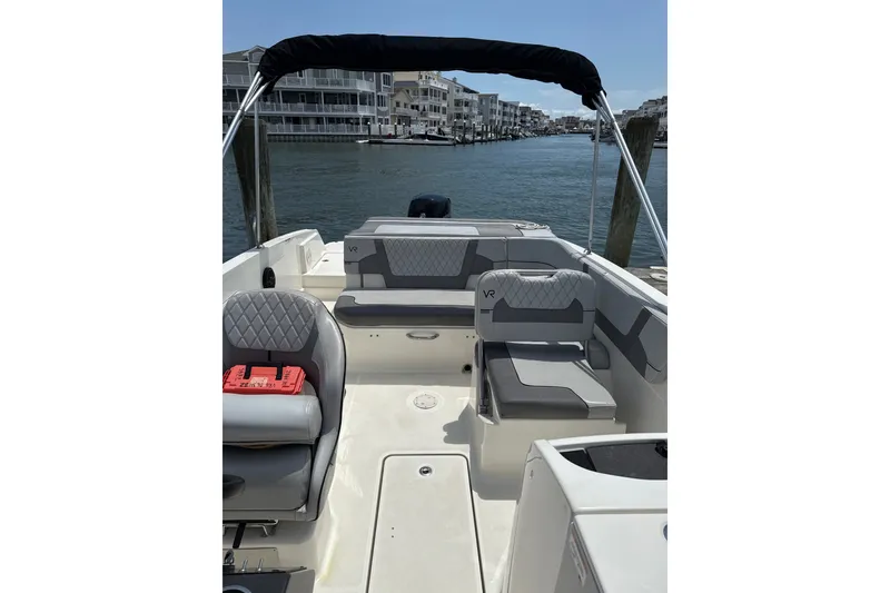 Slide: The Image of 2023 Bayliner VR6 Bowrider OB interior with seating, docked by waterfront homes. - 5