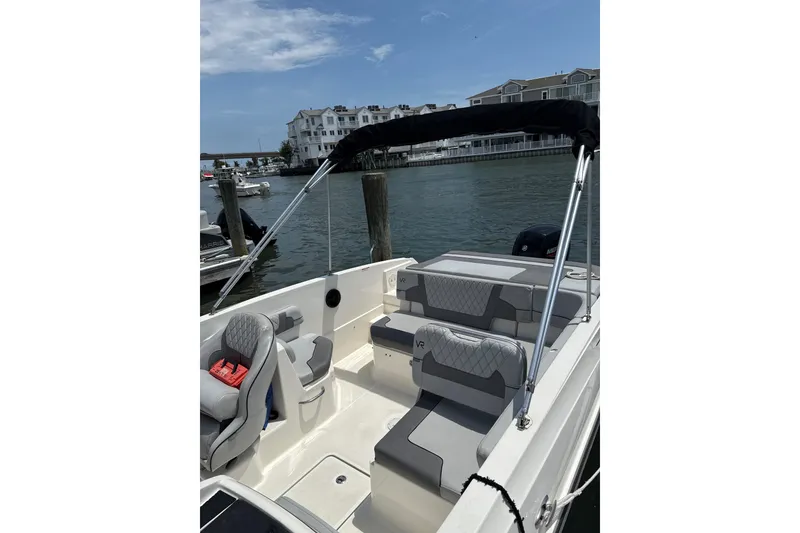 Slide: The Image of 2023 Bayliner VR6 Bowrider OB with sleek seating, docked by waterfront homes. - 7