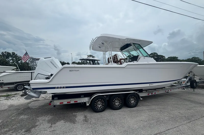 Slide: The Image of 2027 Bertram 34 CC boat on trailer, side view, overcast sky. - 2
