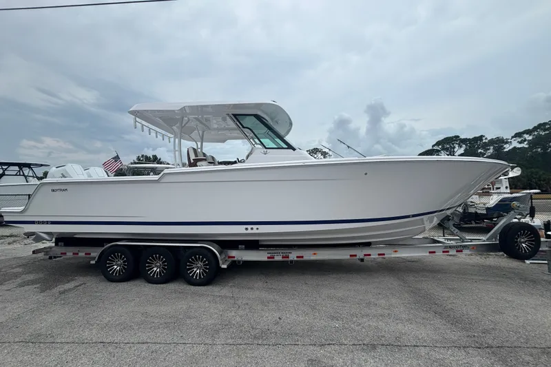 Slide: The Image of 2027 Bertram 34 CC boat on trailer, side view, white hull, overcast sky. - 1
