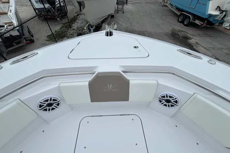 Slide: The Image of 2027 Bertram 34 CC boat interior with seating and speakers, docked in a marina. - 14