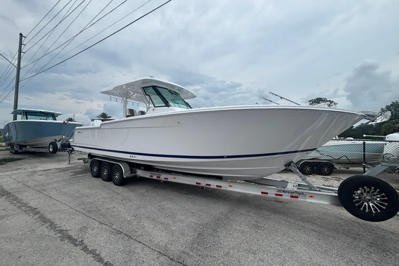 The Image of 2027 Bertram 34 CC boat on trailer, parked outdoors under cloudy sky. - 0
