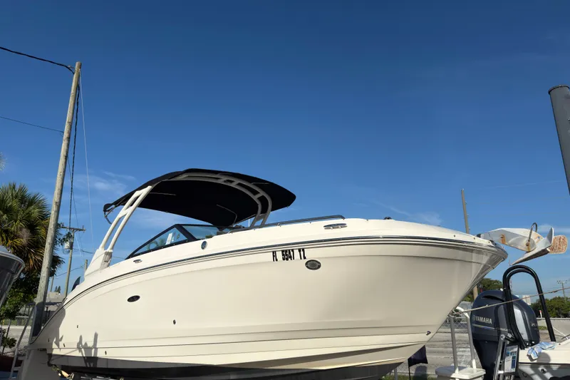Slide: The Image of 2021 Sea Ray SDX 270 boat with black canopy, parked outdoors under clear blue sky. - 2
