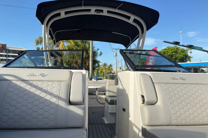 Slide: The Image of 2021 Sea Ray SDX 270 boat interior with seating and canopy under clear blue sky. - 13