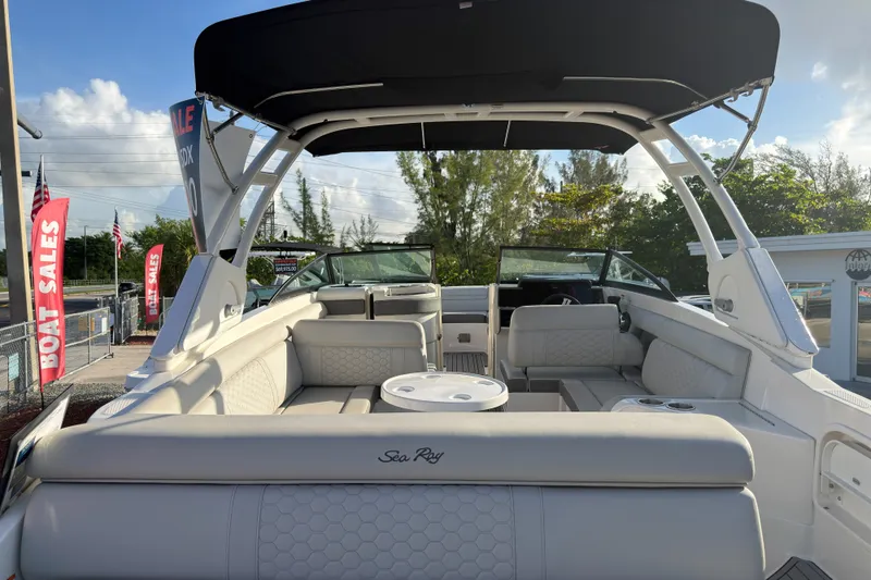 Slide: The Image of 2021 Sea Ray SDX 270 boat interior with seating, canopy, and sale banners in the background. - 15