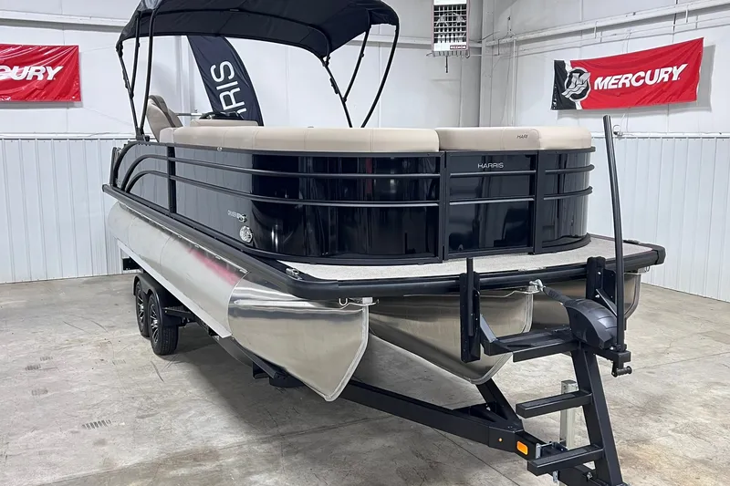 Slide: The Image of 2026 Harris Cruiser 250 pontoon boat in showroom with Mercury banners. - 3