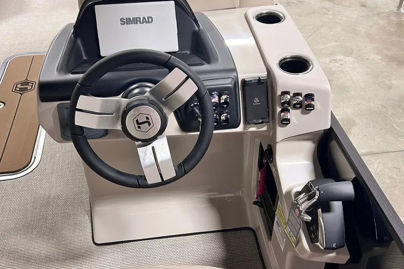 Slide: The Image of 2026 Harris Cruiser 250 helm with steering wheel, Simrad display, and control panel. - 14