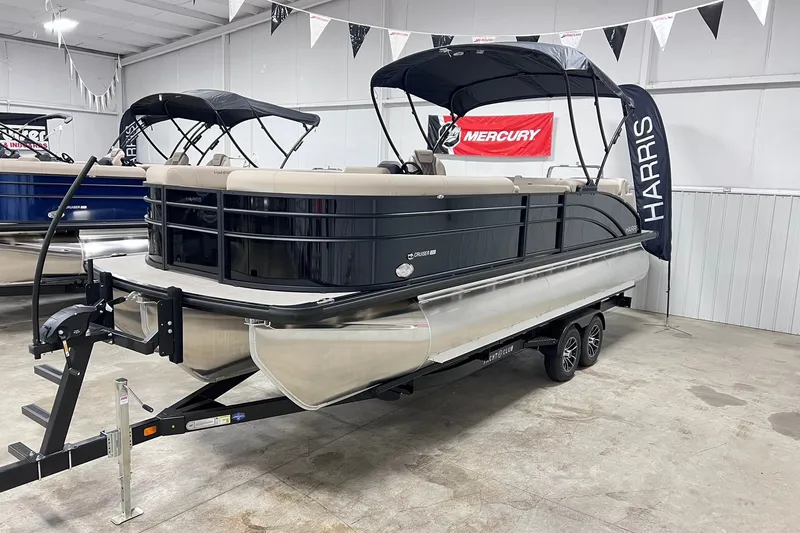 Slide: The Image of 2026 Harris Cruiser 250 pontoon boat displayed indoors on a trailer. - 1