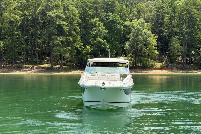 Slide: The Image of 2025 Sea Ray Sundancer 320 cruising on a serene lake with lush forest backdrop. - 13