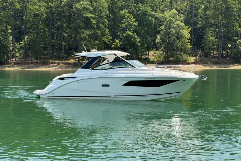 The Image of 2025 Sea Ray Sundancer 320 yacht on serene lake with lush forest backdrop. - 0