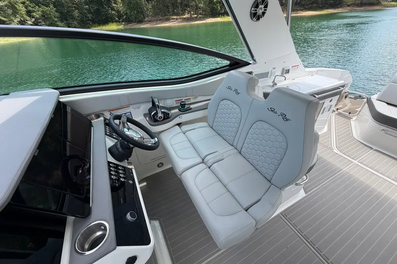 Slide: The Image of 2025 Sea Ray Sundancer 320 cockpit with dual seats, steering wheel, and lake view. - 20
