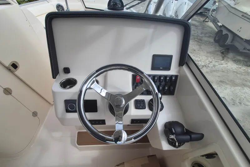 Slide: The Image of 2027 Grady-White Freedom 285 boat helm with steering wheel and control panel. - 9