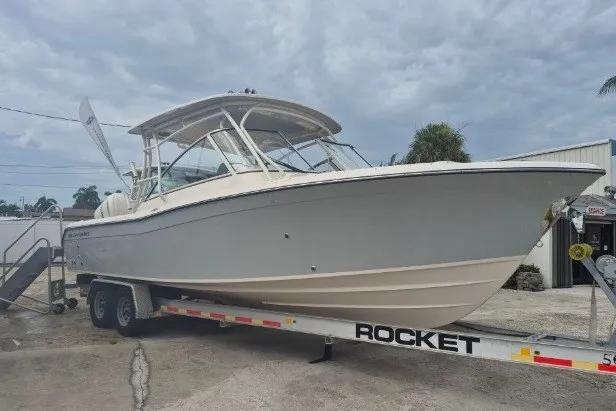 Slide: The Image of 2027 Grady-White Freedom 285 boat on trailer, parked outdoors under cloudy sky. - 2