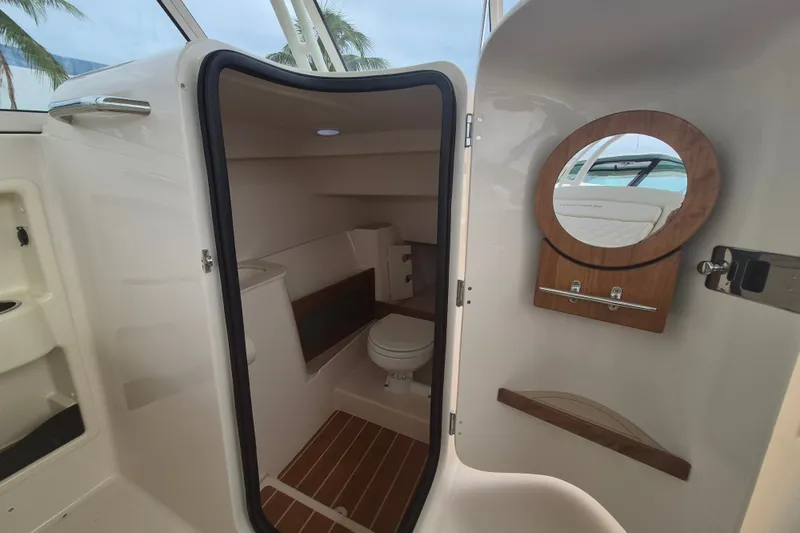 Slide: The Image of Interior of 2027 Grady-White Freedom 285 boat, featuring a compact bathroom with a round mirror. - 14