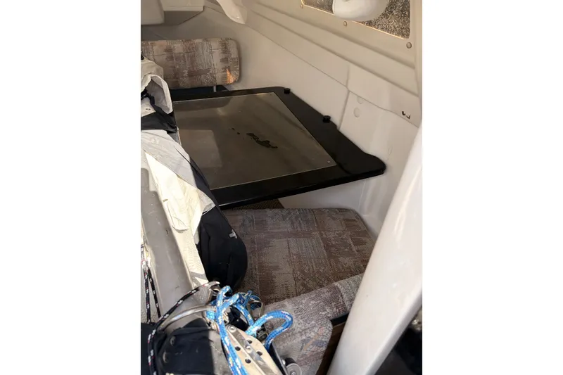Slide: The Image of Interior of a 2000 MacGregor 26X sailboat, featuring seating and a table. - 17