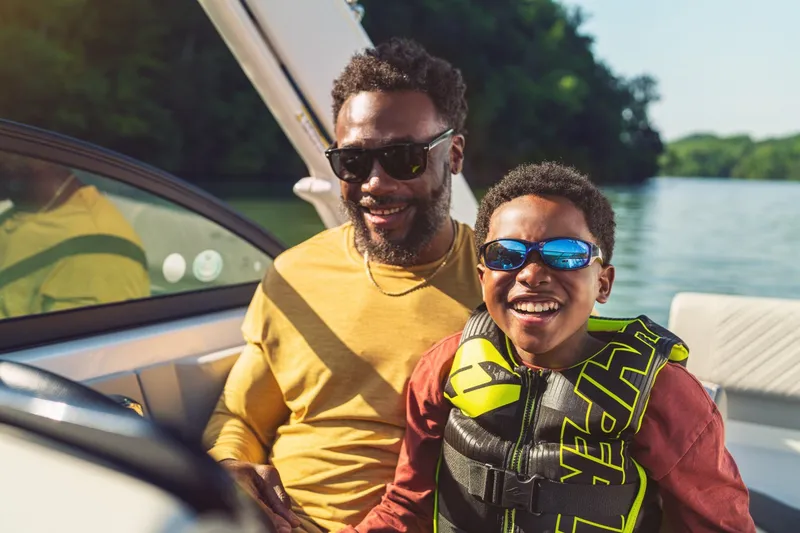 Slide: The Image of A man and child enjoy a boat ride on a Sea Ray SDX 230 Outboard. - 14