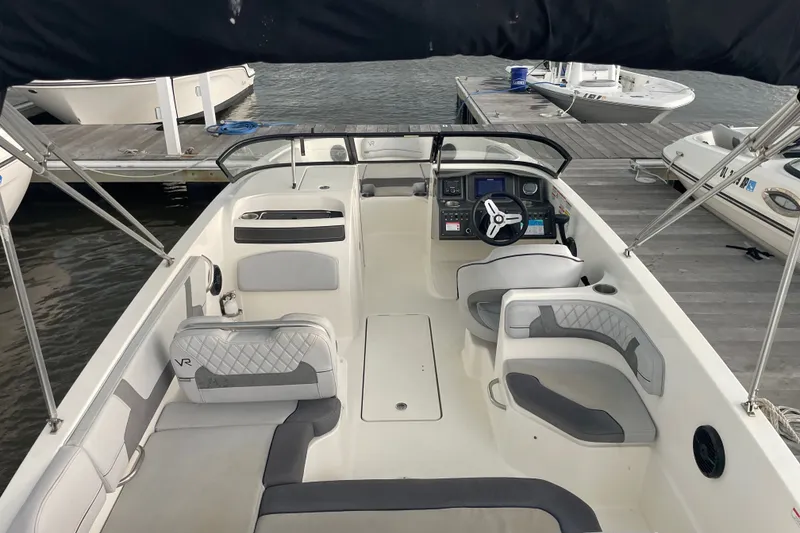 Slide: The Image of 2023 Bayliner VR6 Bowrider OB interior, featuring spacious seating and modern dashboard at dock. - 6