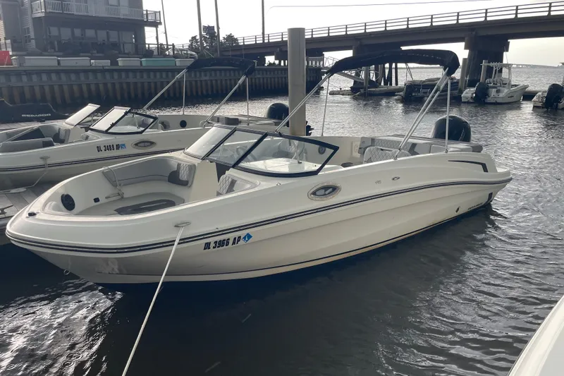 The Image of 2023 Bayliner VR6 Bowrider OB docked near a bridge, ready for adventure. - 1