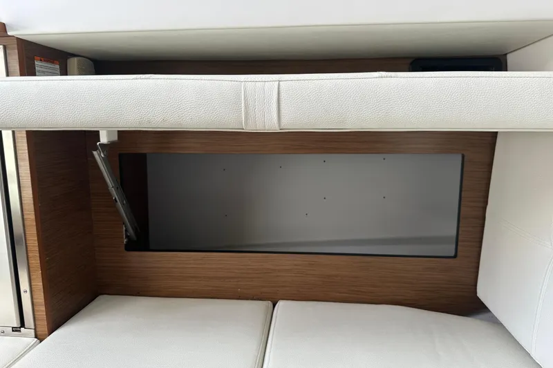 Slide: The Image of 2019 Cruisers Yachts 338 Outboard interior storage compartment with white cushioned seating. - 18