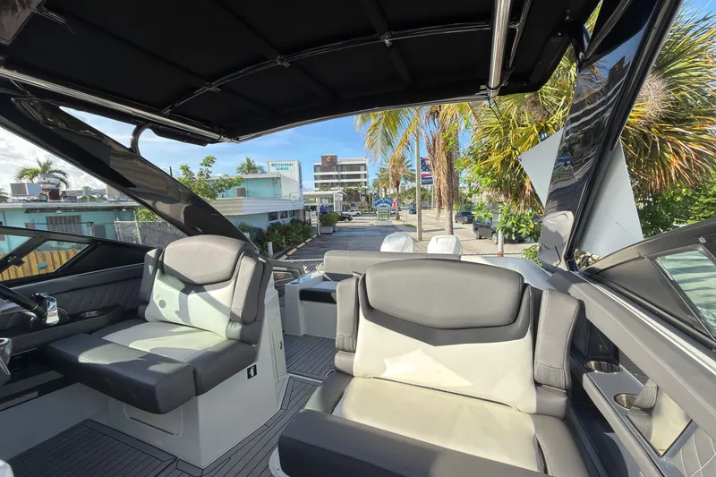 Slide: The Image of 2019 Cruisers Yachts 338 Outboard interior with seating, palm trees, and urban backdrop. - 20