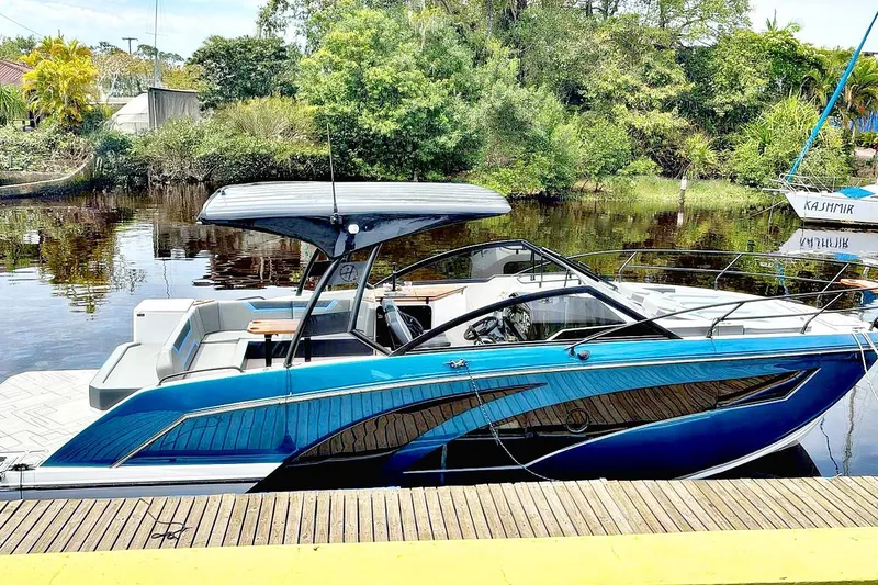 The Image of 2026 Hanover 327 boat docked by a scenic riverside with lush greenery. - 0