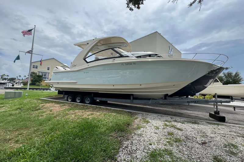 Slide: The Image of 2022 Scout 277 Dorado boat on trailer, parked near marina with flags. - 5