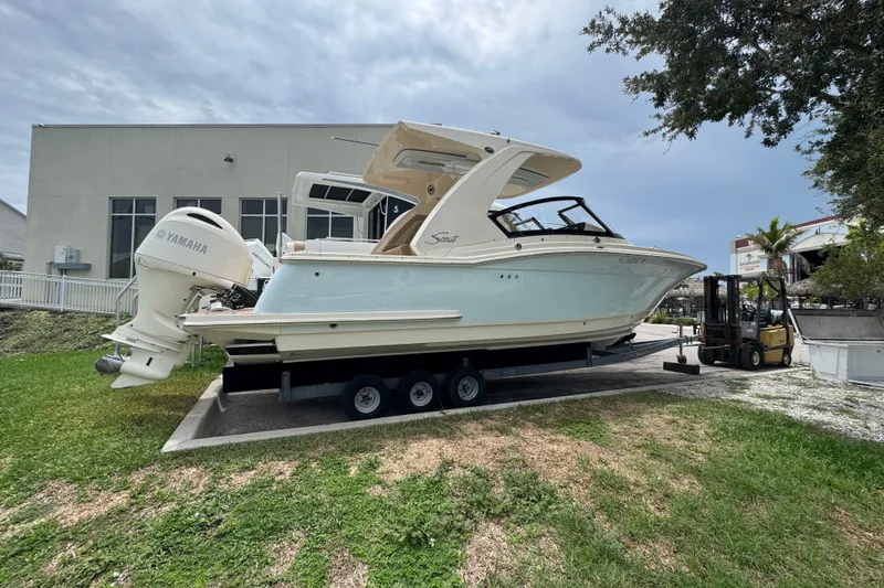 Slide: The Image of 2022 Scout 277 Dorado boat on trailer with Yamaha engines, parked outdoors. - 4