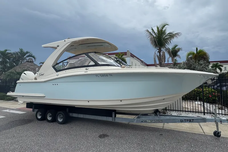 Slide: The Image of 2022 Scout 277 Dorado boat on trailer, parked outdoors under cloudy sky. - 1
