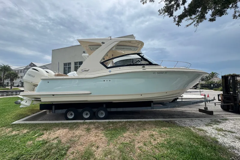 Slide: The Image of 2022 Scout 277 Dorado boat on trailer, parked outdoors under cloudy sky. - 3