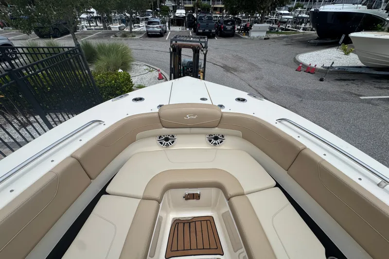 Slide: The Image of 2022 Scout 277 Dorado boat with beige seating and wood accents at a marina. - 13