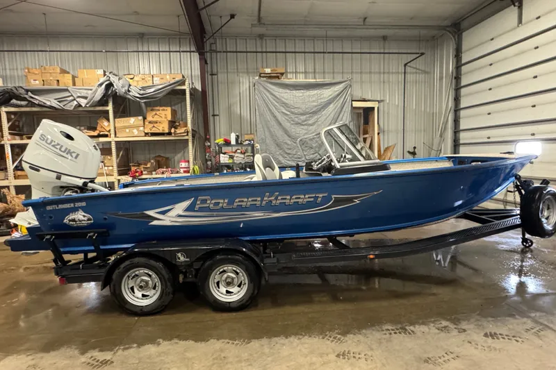 The Image of Blue 2023 Polar Kraft Outlander 2010 WT boat with Suzuki engine in a garage. - 0