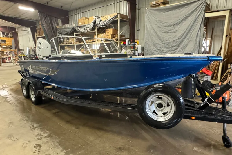 Slide: The Image of 2023 Polar Kraft Outlander 2010 WT boat on trailer in warehouse setting. - 2