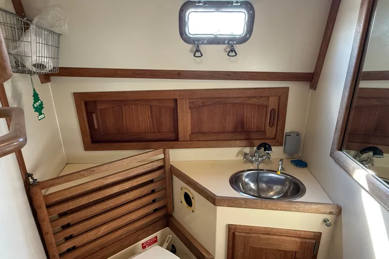 Slide: The Image of Interior of 1994 Pacific Seacraft Crealock 37 yacht bathroom with wooden cabinetry and stainless steel sink. - 47