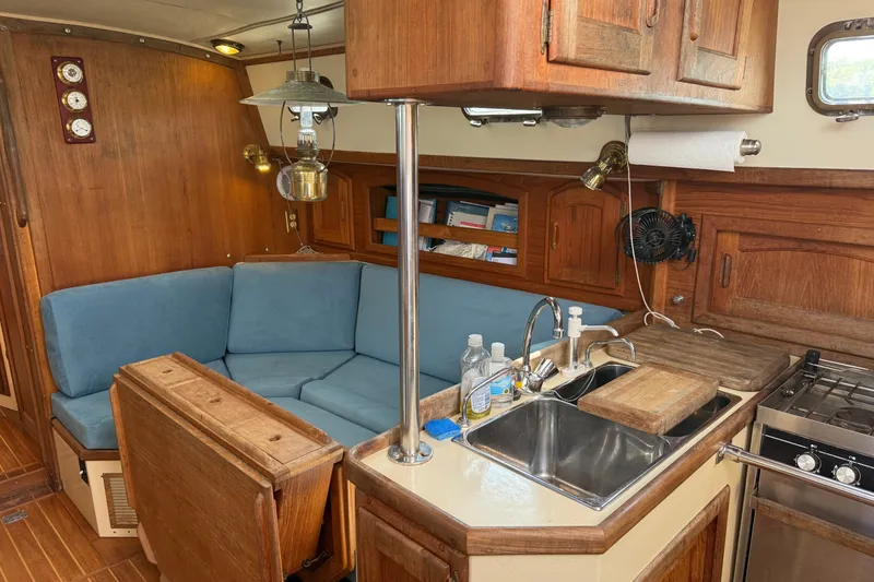 Slide: The Image of Cozy 1994 Pacific Seacraft Crealock 37 yacht interior with wooden cabinetry and blue seating. - 13