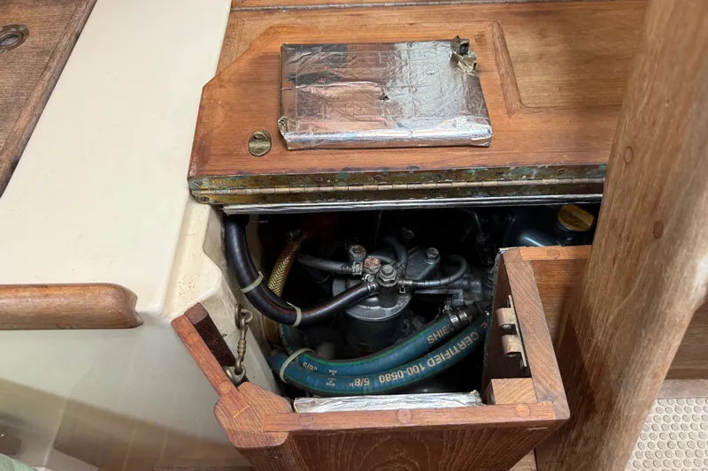 Slide: The Image of Engine compartment of a 1994 Pacific Seacraft Crealock 37 sailboat, showing hoses and wooden paneling. - 85