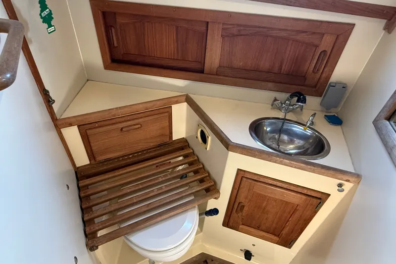 Slide: The Image of 1994 Pacific Seacraft Crealock 37 yacht bathroom with wooden cabinetry and stainless steel sink. - 49